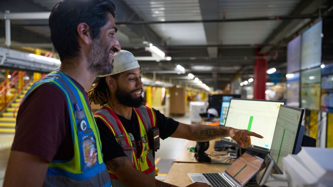 Smiling coworkers in safety vests analyzing inventory system
