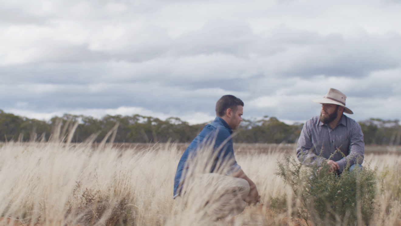 Two men sitting in a field. 