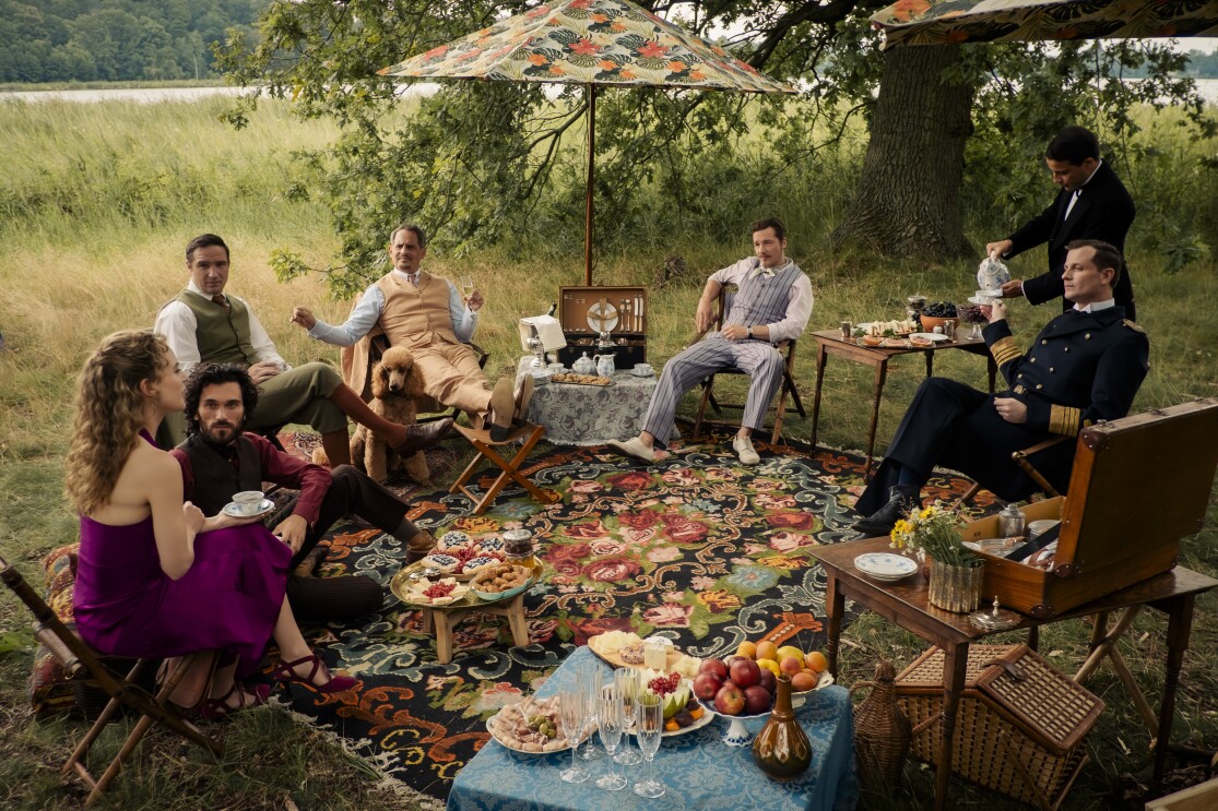 Elegantes Picknick im Stil der 1920er Jahre auf einer Wiese mit reichhaltigem Buffet