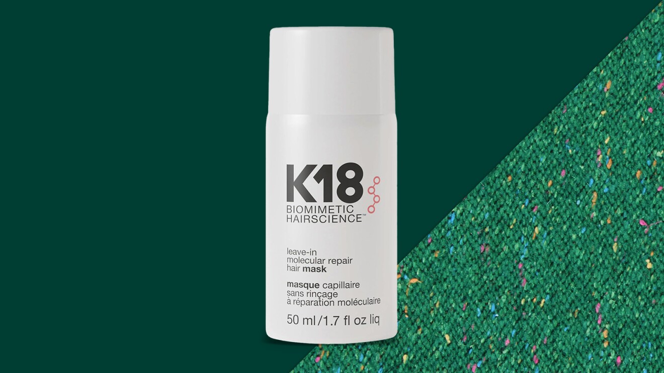 White bottle of K18 hair treatment against emerald background