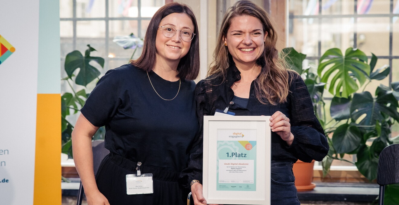 Fiona von Prónay und Jennifer Nicolay (v.l.) von der Azubi Digital Akademie gGmbH stehen auf der digital.engagiert-Bühne und halten ihre Urkunde für den ersten Platz in die Kamera.