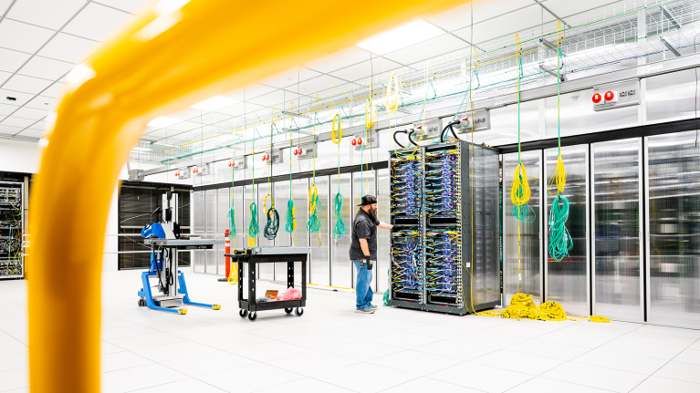 Data center server room with colorful network cables and technician