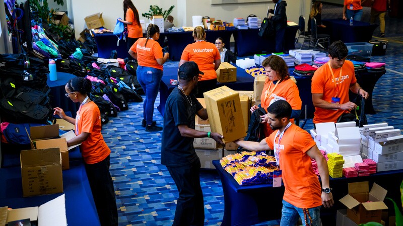 Amazon Volunteers in orange shirts organizing donations at community event