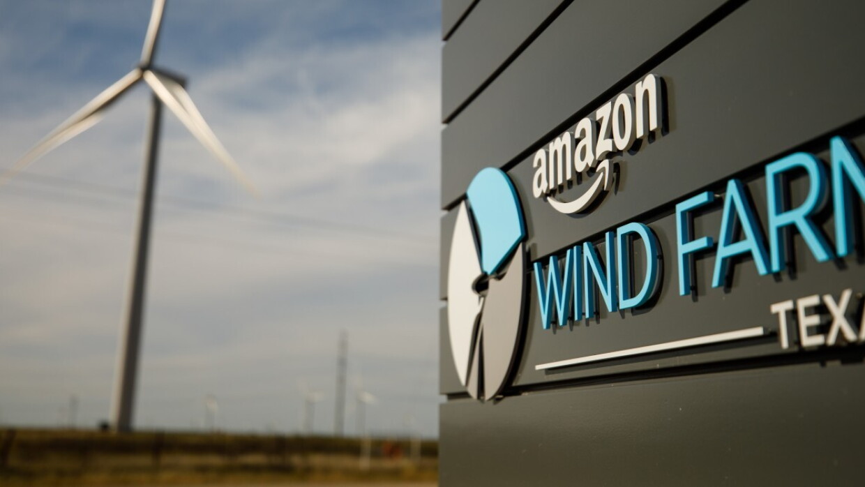 Logo Amazon oraz tekst 'Wind Farm Texas' na czarnej ścianie, w tle farma wiatrowa