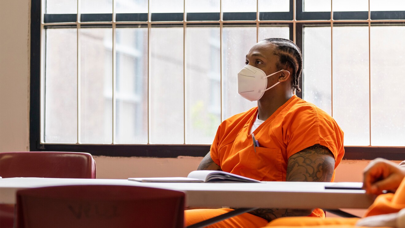 A photo of an inmate in a Washington, D.C. jail, sitting at a desk with a notebook on it.