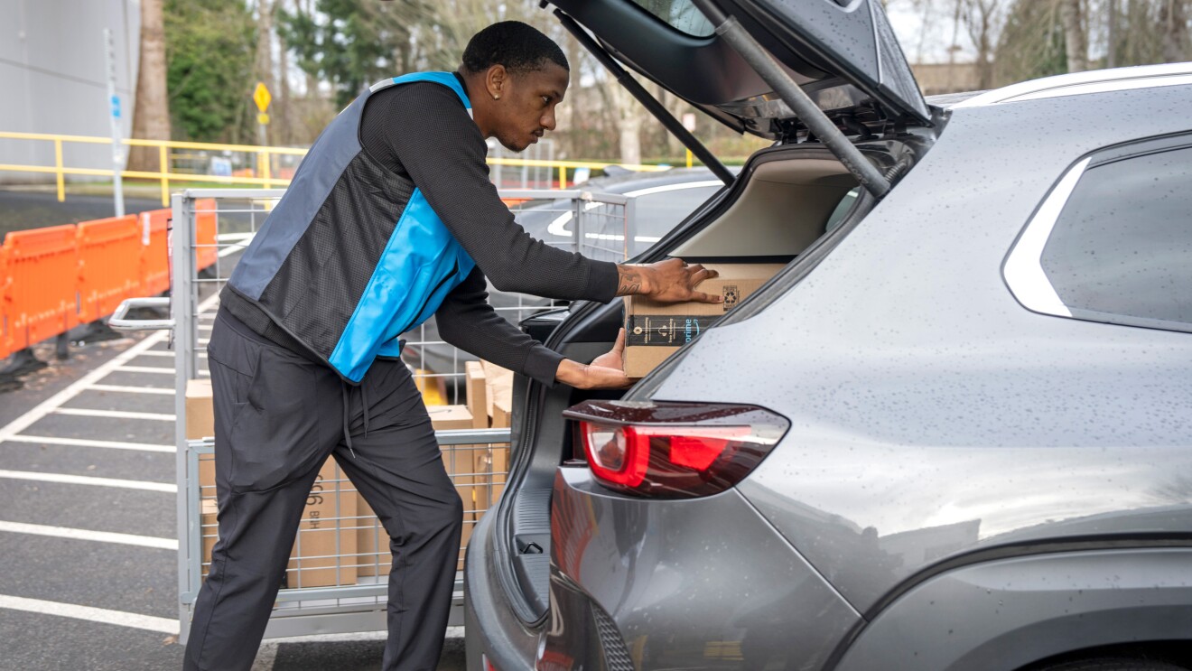 A photo of Quarterback Michael Penix, Jr. placing an Amazon package in the trunk of a car.