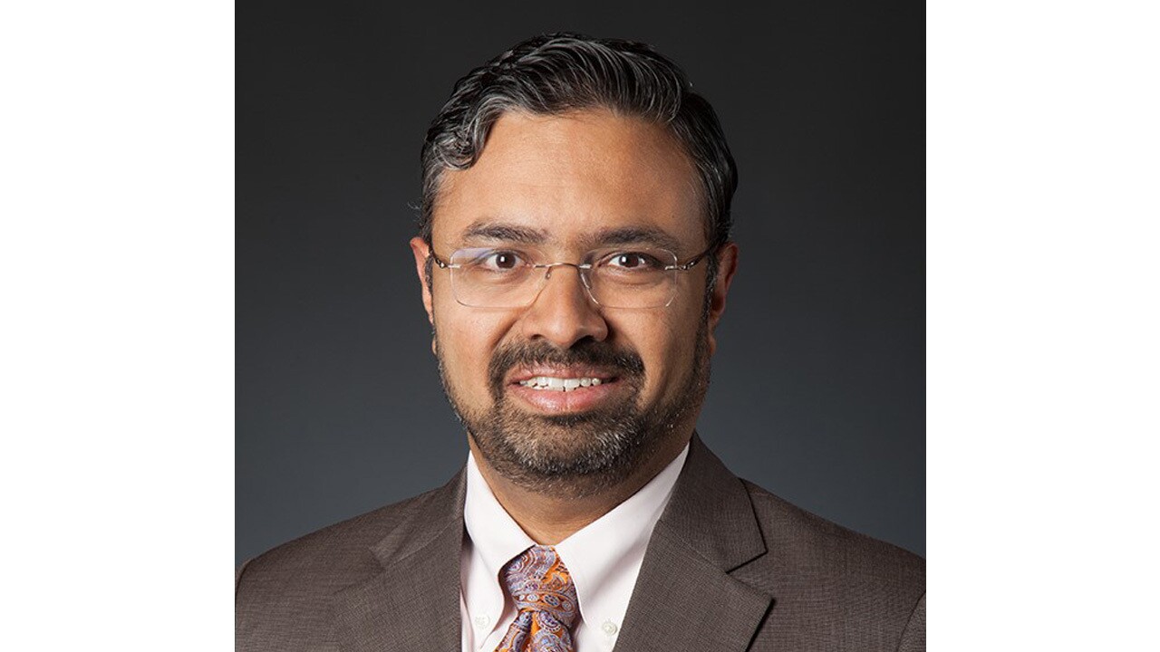 A headshot image of a man against a black background.