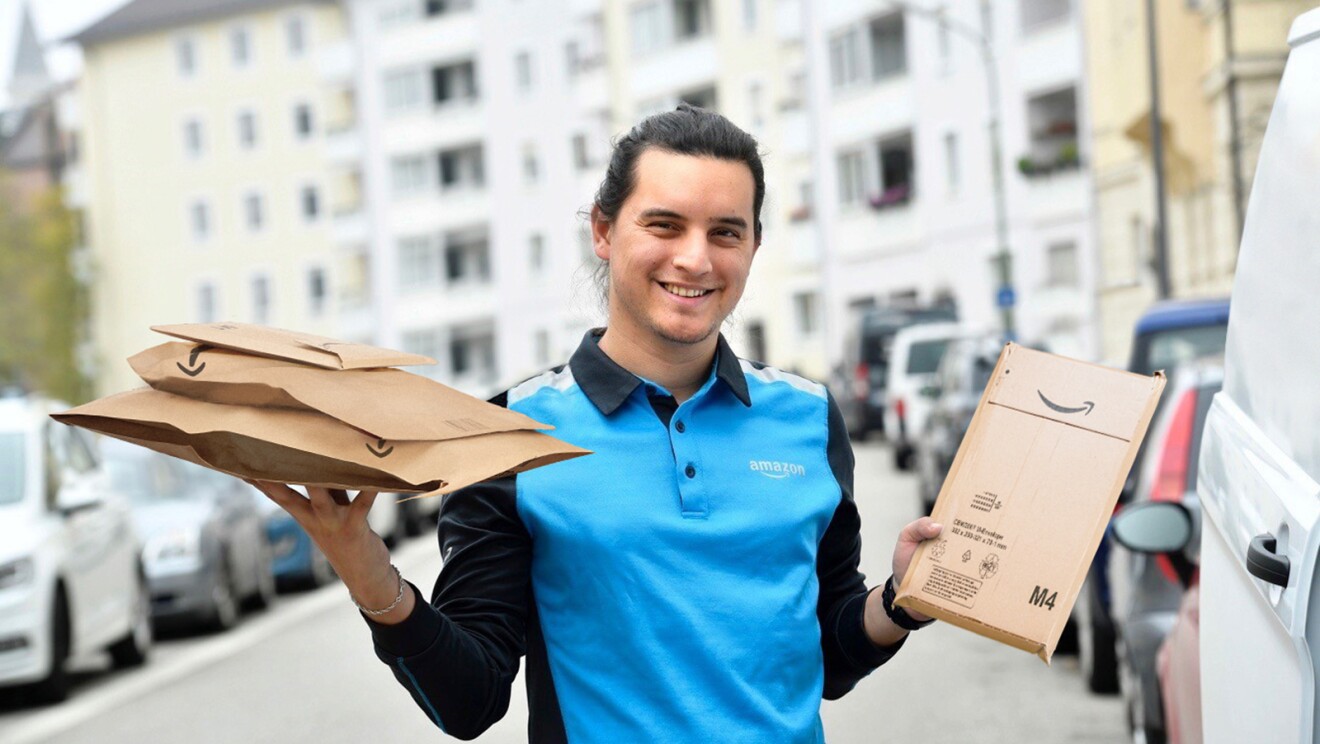 An Amazon Delivery Associate holding Amazon paper and cardboard packaging