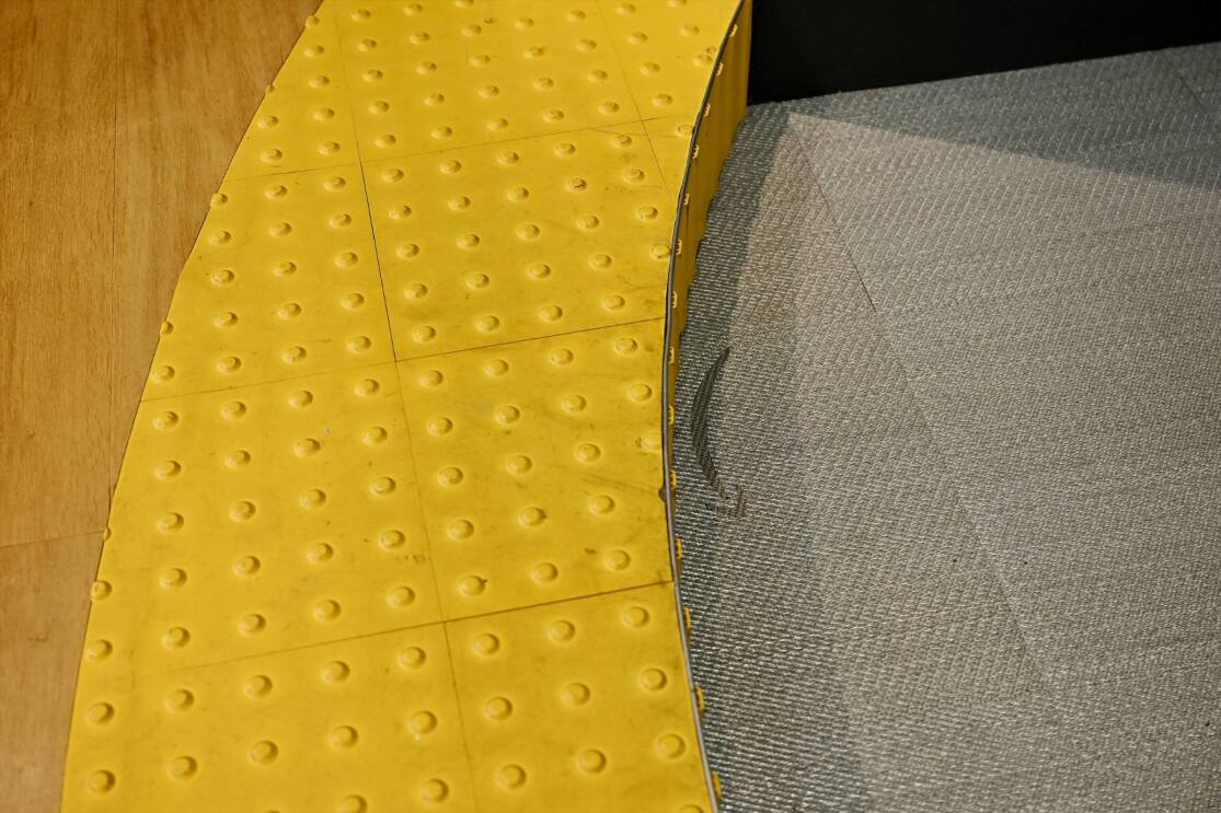 黄色いブロックタイルのある段差。床に灰色のAmazonのスマイルロゴが見える。