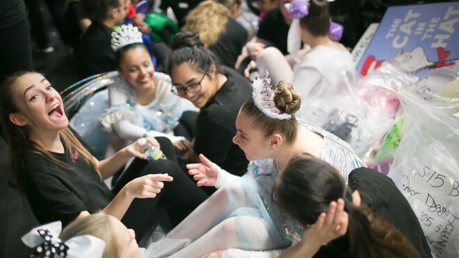 微笑的少年and孩子们坐在一起。一些穿裙子和头饰。一些穿全黑t恤和裤子。