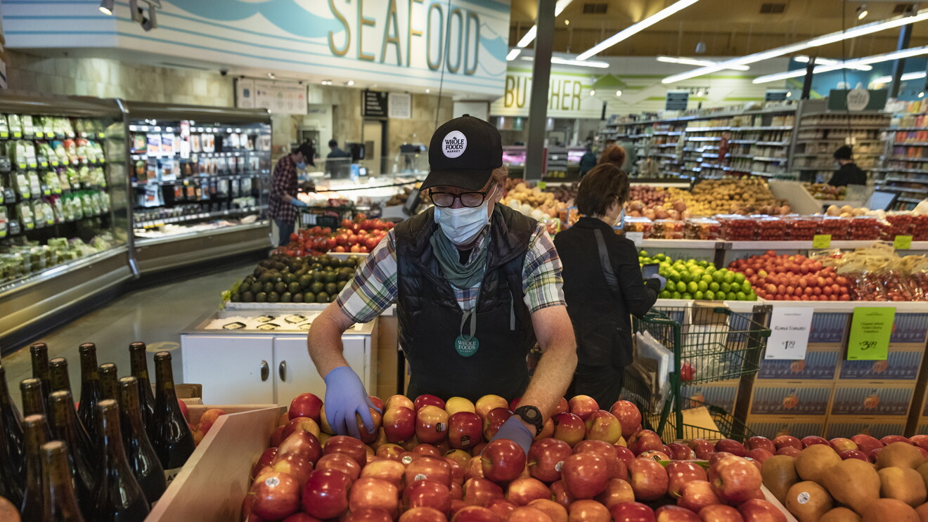 A Whole Foods Market Team Member organizes apples in the grocery store. 