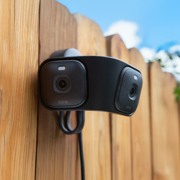 Blink security camera mounted on wooden fence under blue sky