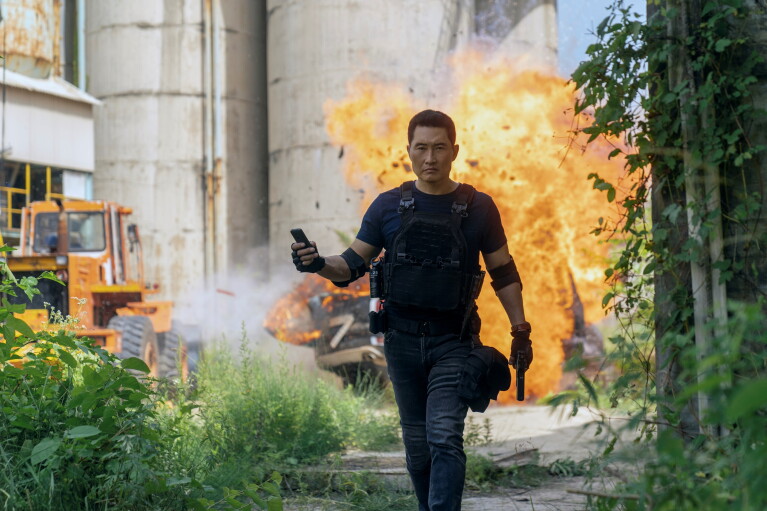 Man in tactical gear walking away from explosion