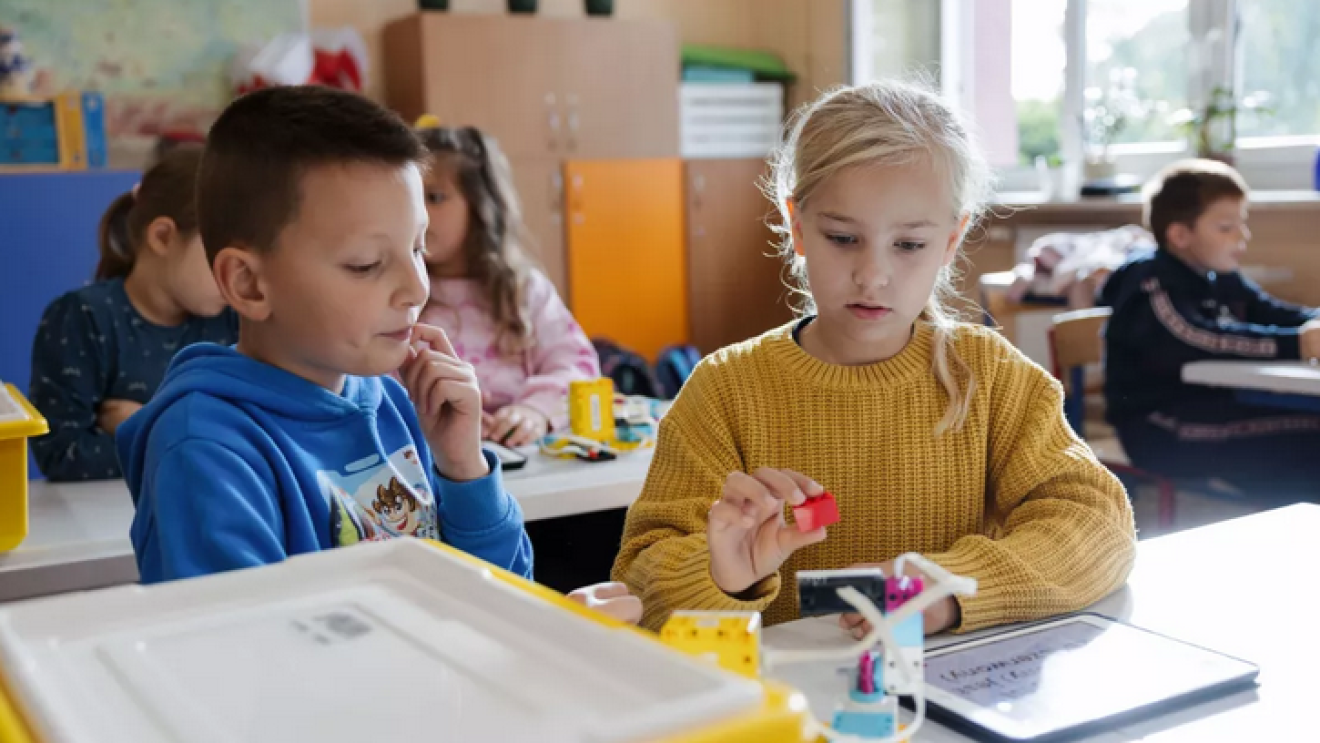 Zwei Kinder in einem Klassenzimmer arbeiten an einer Übung mit einem Tablet