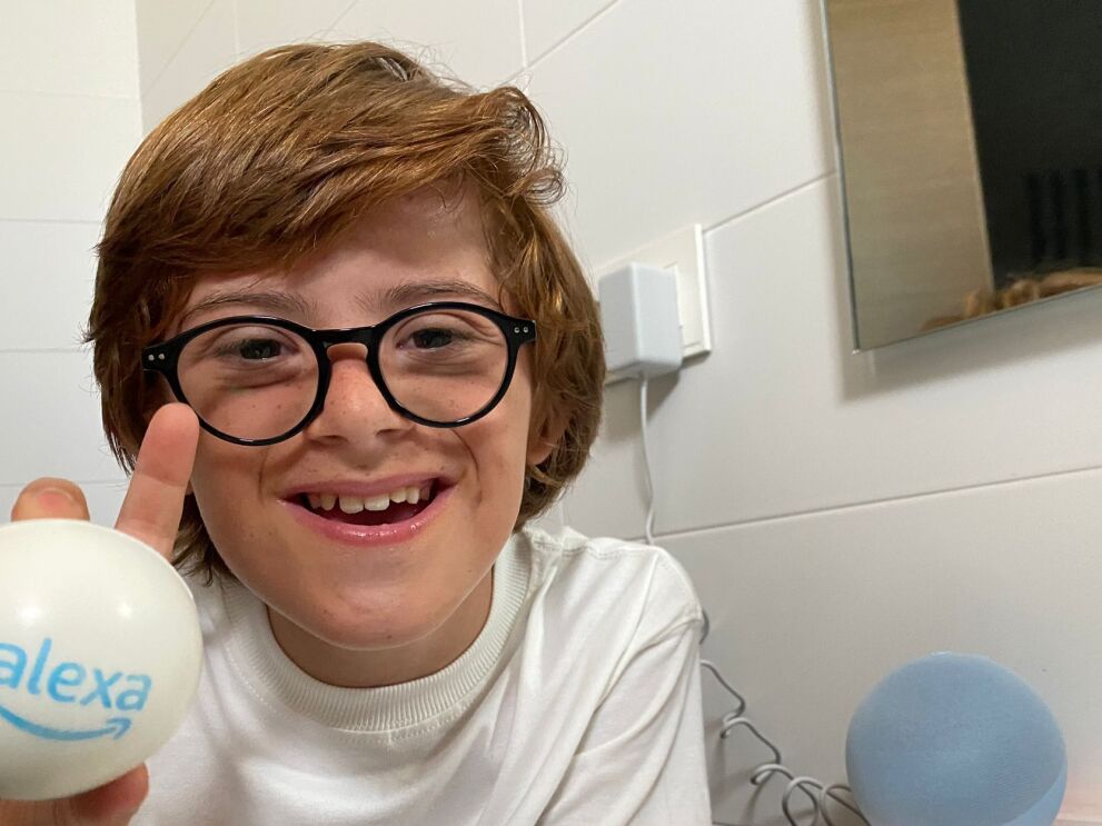 Pleayo en el baño con un dispisitivo de voz con la luz naranja operativa y en la mano derecha una bola de goma con el logo de Alexa.