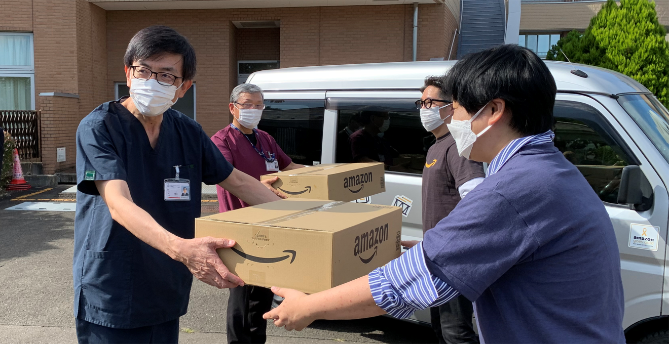病院のみなさんにAmazonのダンボールにはいった寄付品を手渡す様子