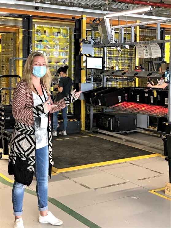 Eine blonde Frau mit Mundschutz in einer Lagerhalle