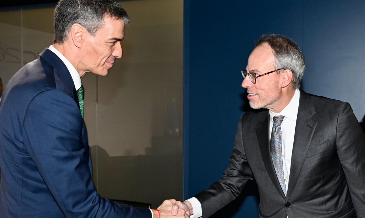 An Amazon executive and a Spanish government representative in suits shaking hands during formal meeting