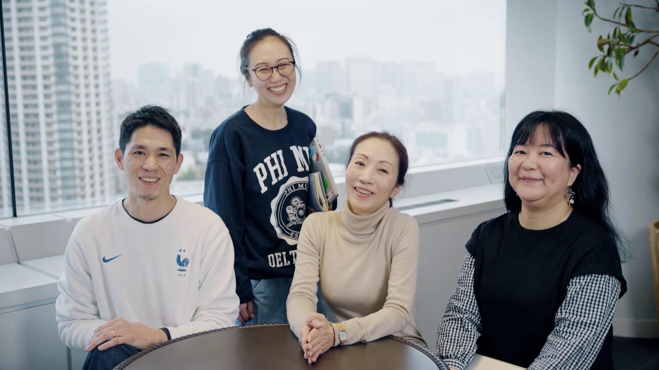 3人の女性と1人の男性がオフィスのような部屋でテーブルの周りに座っている。