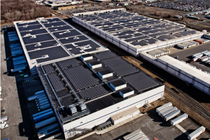 Aerial view of of two Amazon fulfilment facilities with solar systems on their rooftops.