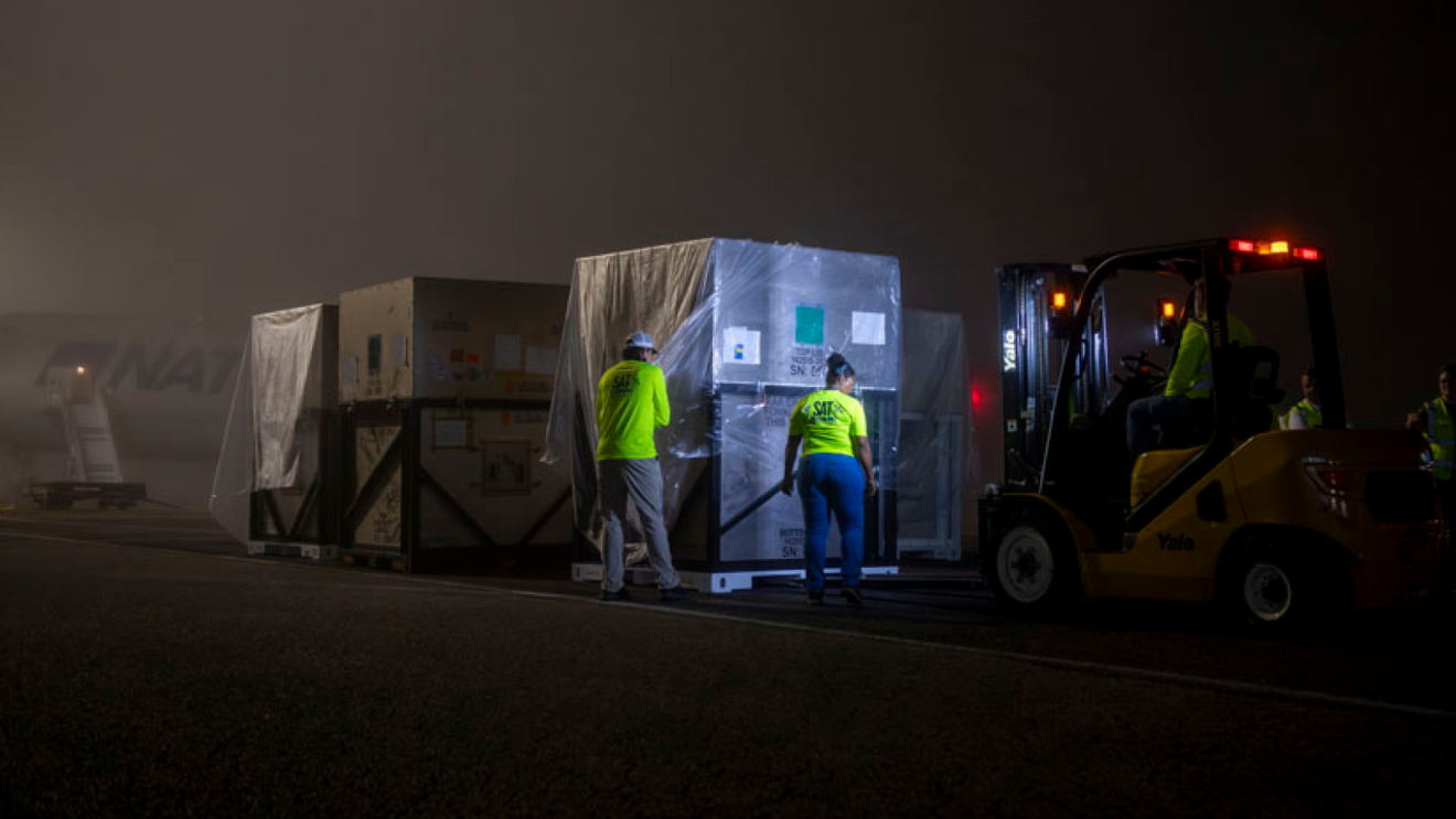 Ouvriers en équipement haute visibilité déchargeant de grandes caisses la nuit