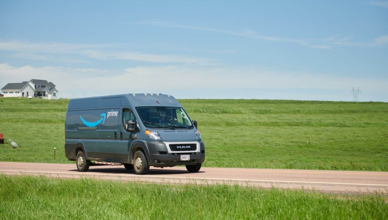 Amazon Prime delivery van on rural road with farmhouse in background
