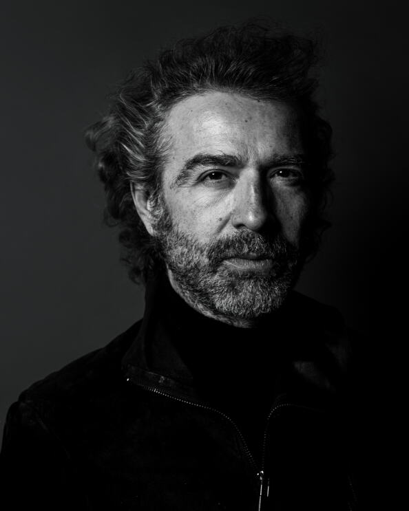 Schwarz-weiß Porträt-Foto von Christof Straub, CEO von Global Rockstar, er trägt Vollbart, das Haar ist leicht gelockt und grau meliert. Er trägt einen schwarzen Rollkragenpullover und darüber eine schwarze Jacke.