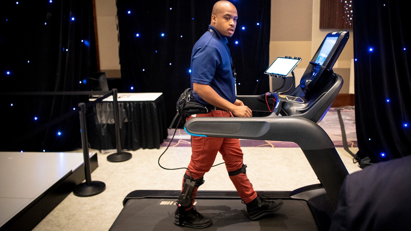 一个男人带着设备在跑步机上行走的画面。