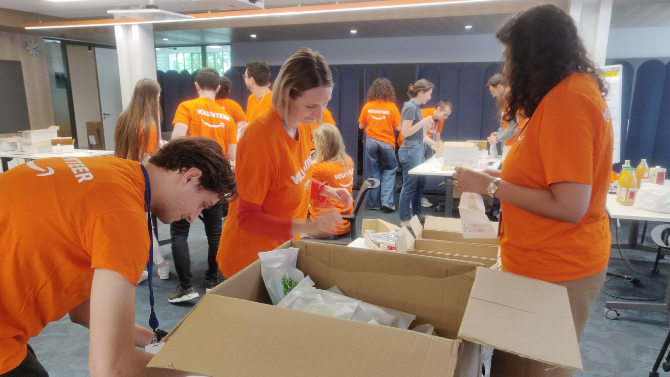 Amazon employees wear orange "volunteer" T-Shirts and pack hygiene kits.