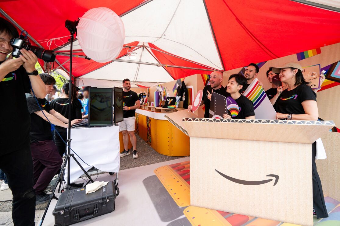 大きなダンボールのようなデコレーションの中で男性4人と女性1人がポーズをとっている。その前には彼らの写真を撮っているカメラマン