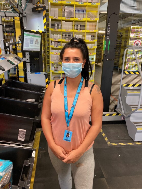 Danelle Ferguson, associate at Amazon's fulfilment centre in Durham, standing at her workstation, wearing a facemask.