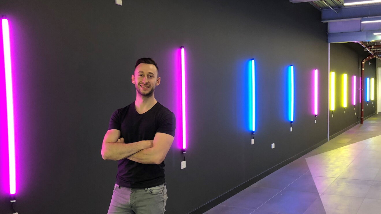 Luca Sale stood with arms folded against a colourful background at Amazon 