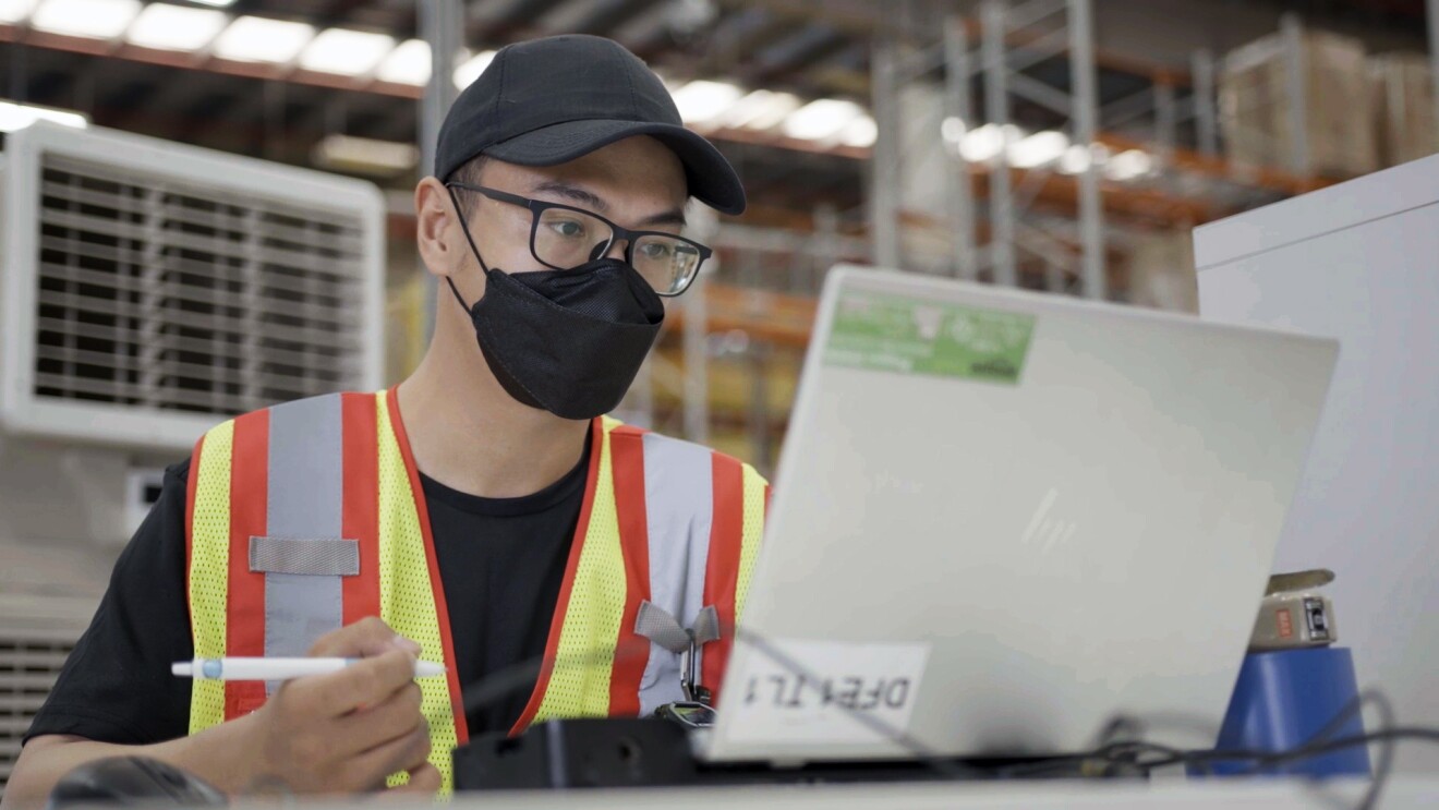 Amazon associate Muhammad Izuan Khairudin is seen working on his laptop at Amazon's Fulfillment Center in Singapore