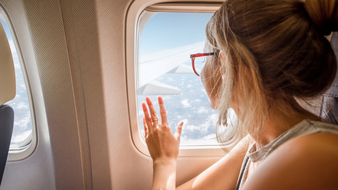 A woman looks out of the airplane. 