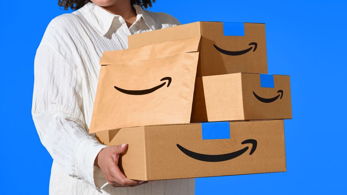 Person holding stack of Amazon delivery boxes with smile logo