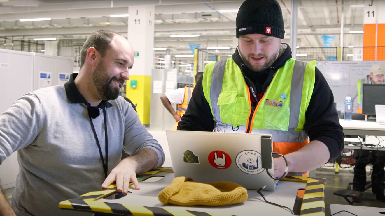 Dennis mit Kolleginnen und Kollegen an seinem Arbeitsort, dem Amazon Logistikzentrum in Oelde.