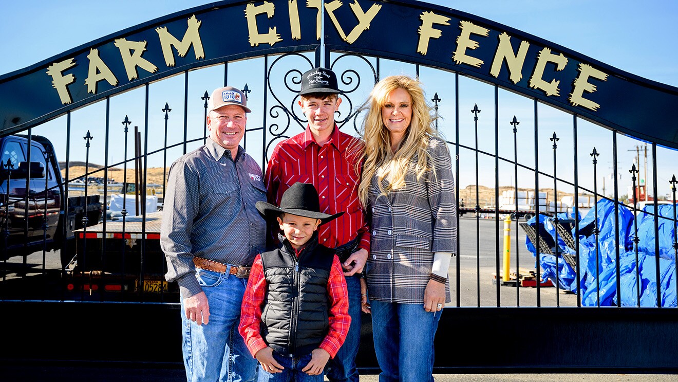 A photo of Shawn Eng and his family standing in front of a gate that displays the name, "Farm City Fence"