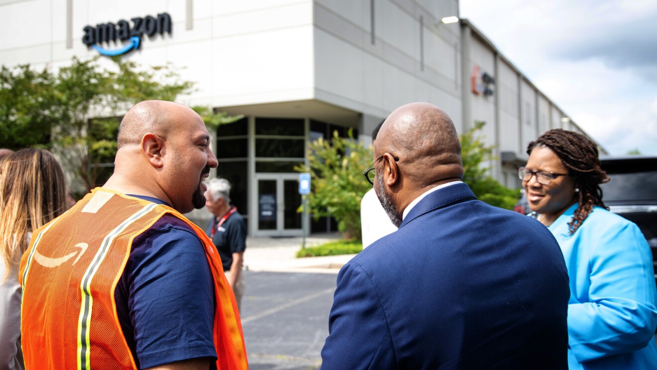 An image of Abe Diaz speaking with two other people outside of an Amazon fulfillment center in Atlanta where they have a disaster relief hub.