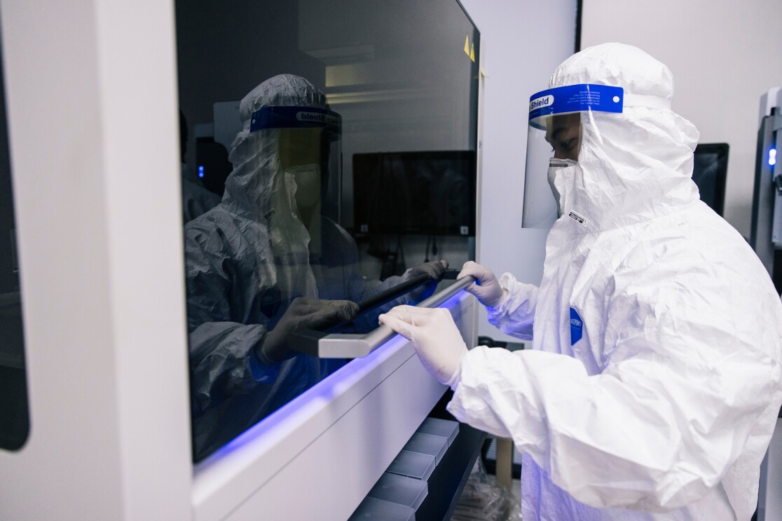 A person in PPE closes a piece of lab equipment.