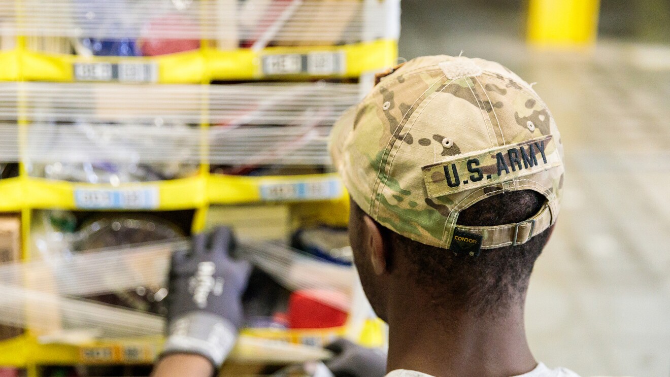 一名戴着美国陆军帽子的男子在亚马逊物流中心工作。