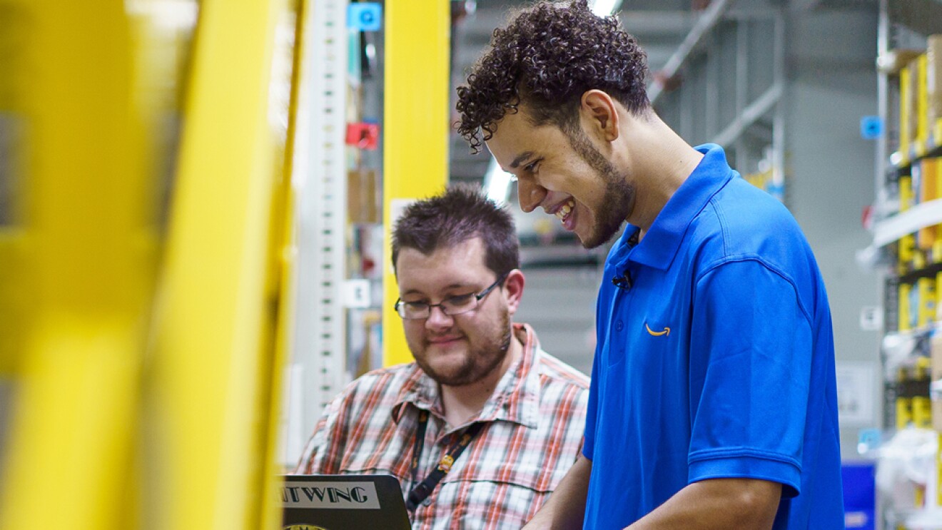两个人并排站在笔记本电脑前工作。