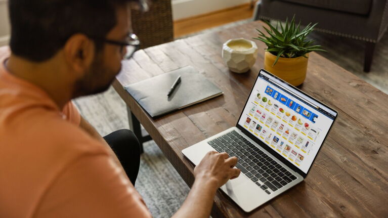 Person using laptop to browse online shopping website at wooden table