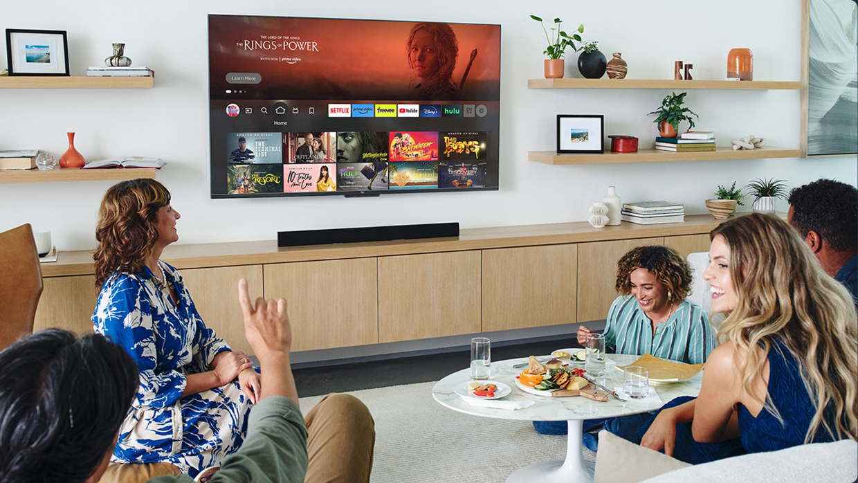 En el salón de una casa están cinco personas tomando un aperitivo y escogiendo qué ver en la televisión. 