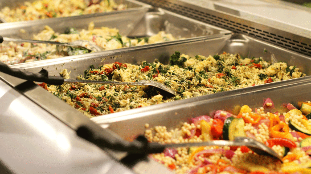 An image of several bins at a bar of food with various pre-made salad options.