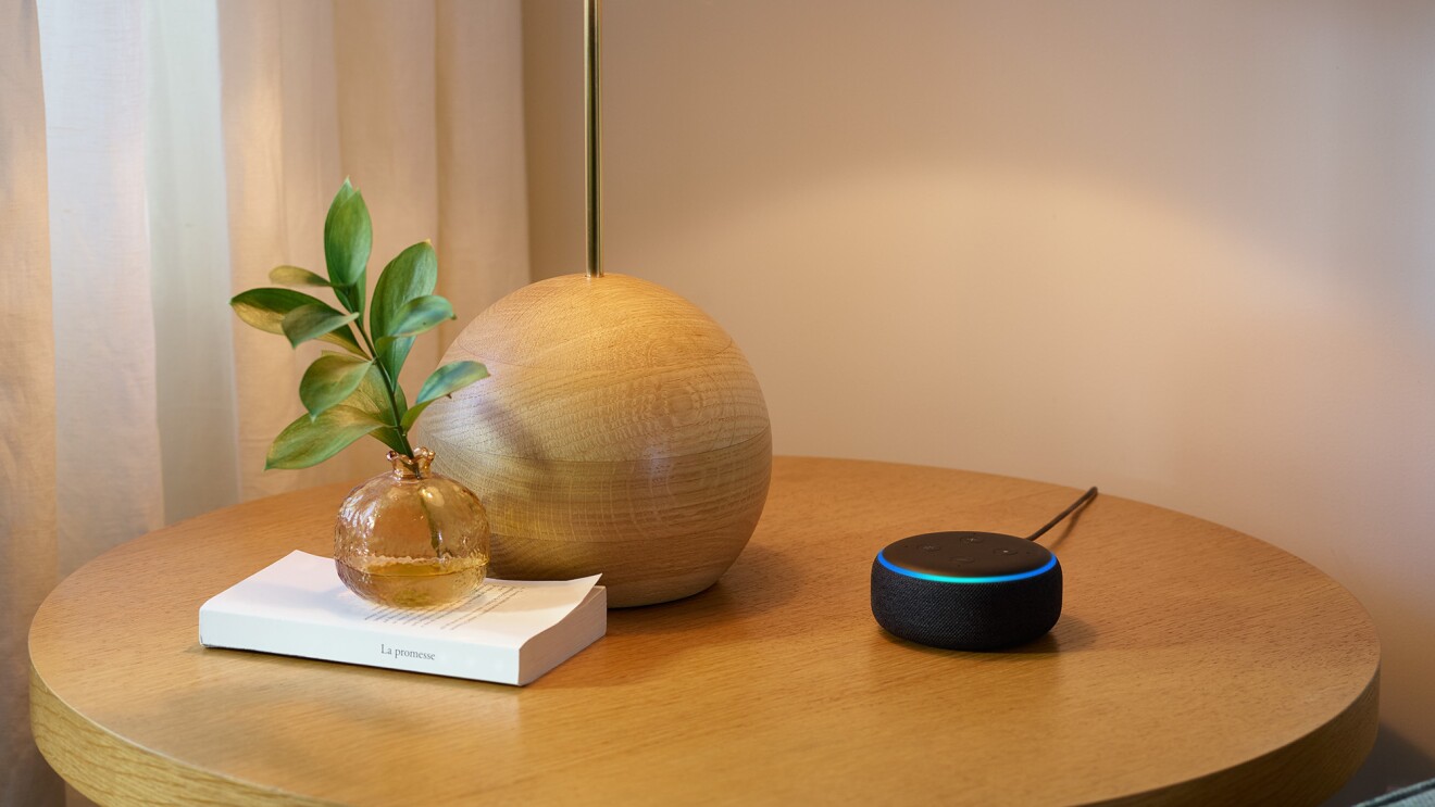 A new Echo Dot device on a side table, next to decorative objects.