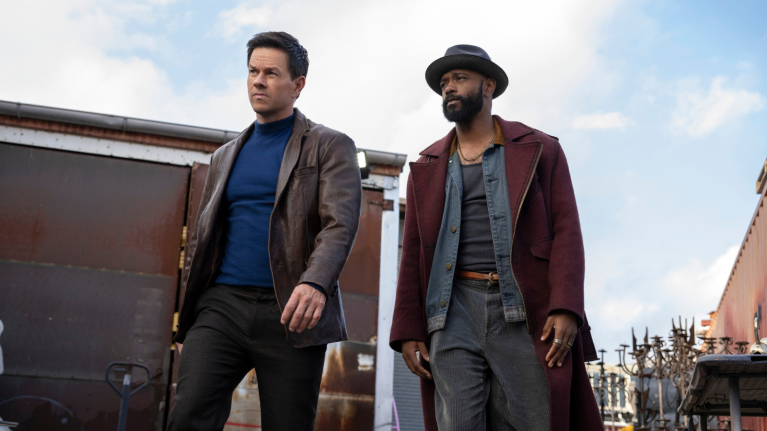 Two men in stylish coats walking purposefully near train cars