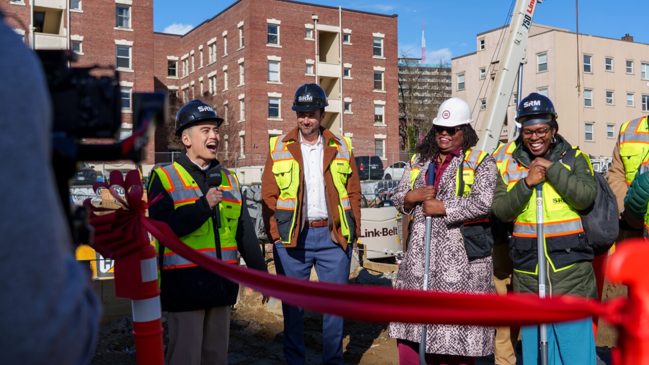 Construction team celebrating at project site with red ribbon