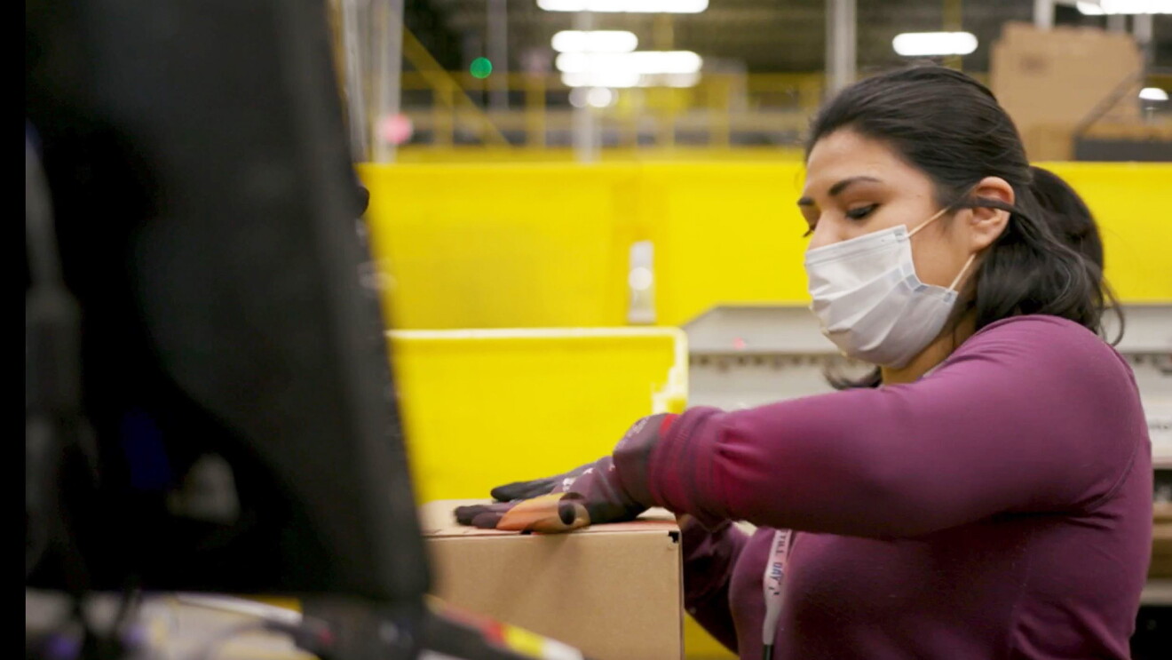 Amazon employee performing work duties while wearing a mask, during COVID-19 pandemic.