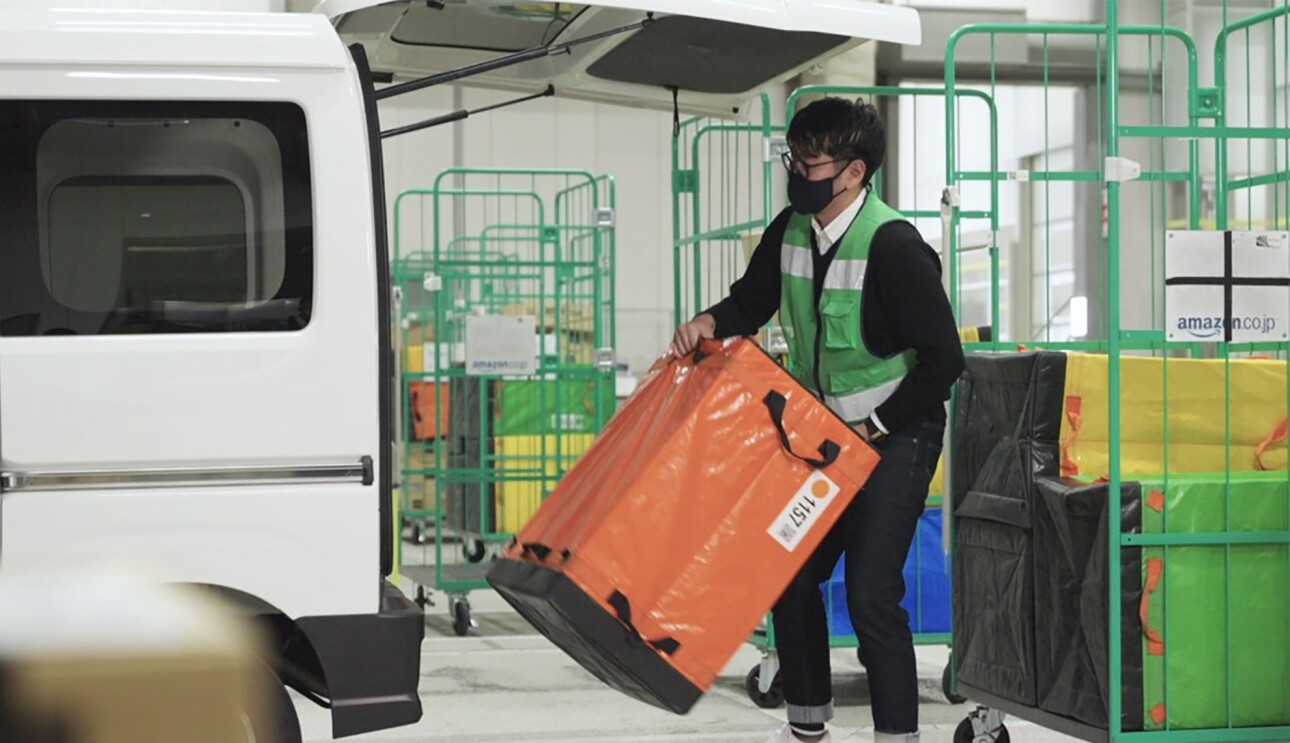 軽自動車の荷台に荷物を積みこむ男性