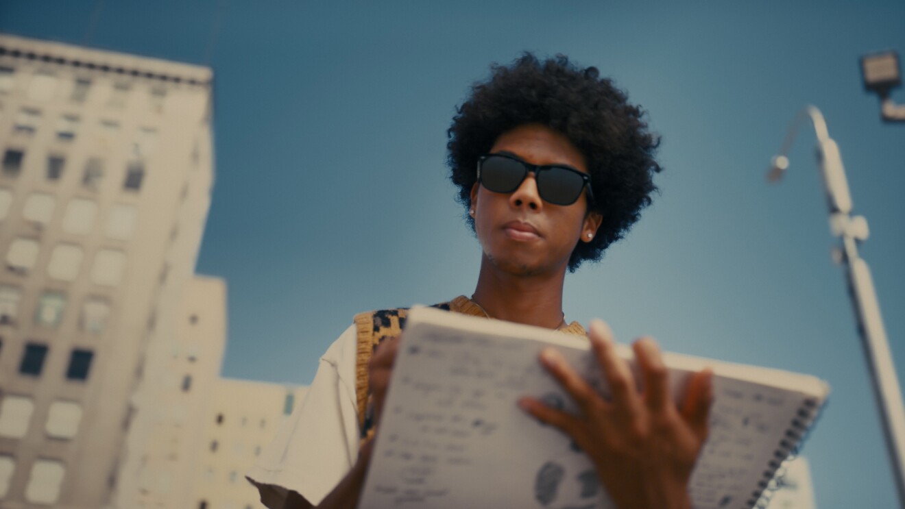 An image of a person using smart sunglasses and holding a notebook. 